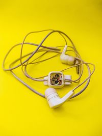 High angle view of in-ear headphones on yellow background