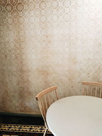 Empty chair and table against wall at home