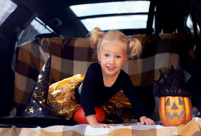 Portrait of cute girl sitting in car trunk