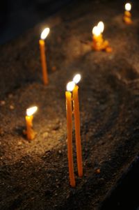 High angle view of lit candles burning in the dark