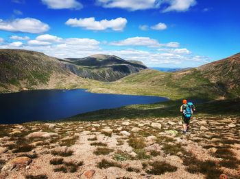 Rear view of man walking on mountain against sky