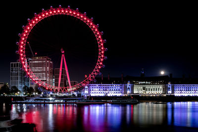 Illuminated ferris wheel in city at night