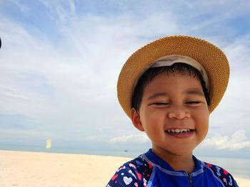 Portrait of smiling boy on beach against sky