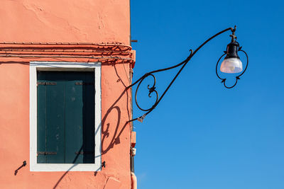 Low angle view of electric lamp against building