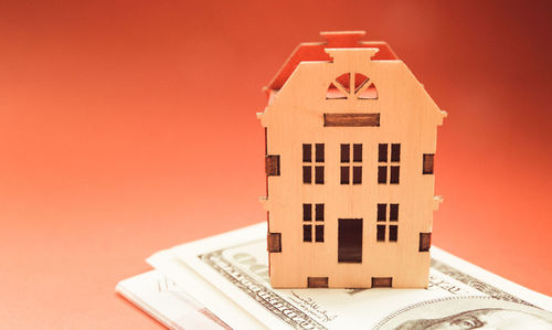 Close-up of house model and currency against red background