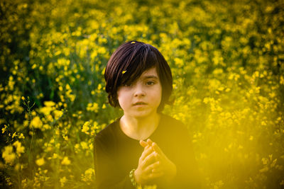 Young woman standing amidst yellow flowers