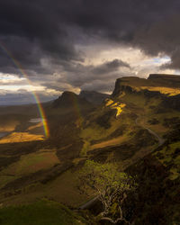 Scenic view of rainbow in landscape during sunset