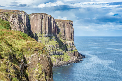 Scenic view of cliff by sea against sky