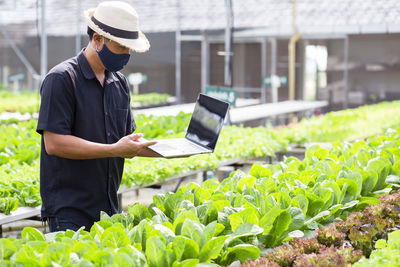 Man holding mobile phone while standing on farm