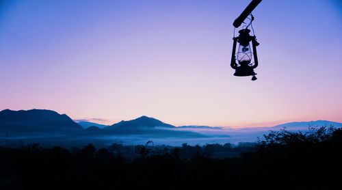 Silhouette trees against mountains during sunset