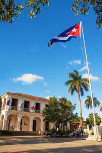 Low angle view of flag by building against sky