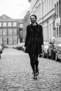 Full length portrait of young woman standing in city