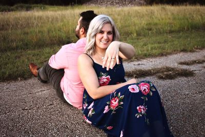 Portrait of smiling young couple sitting on grass