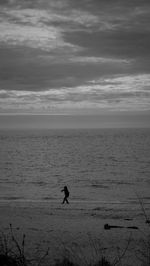 Silhouette people on beach against sky at dusk