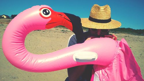 Man blowing pink toy at beach