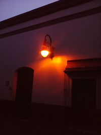 Illuminated building against sky during sunset