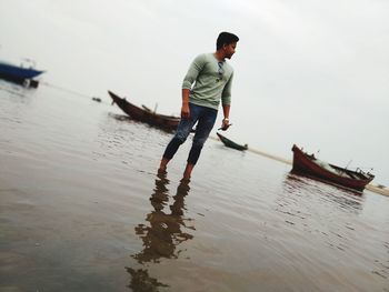 Man standing on boat in sea against sky