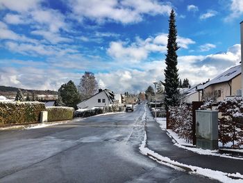 Snow covered road by trees against sky