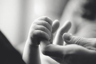 Close-up of baby hand holding mother finger at home
