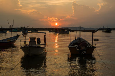 Boats moored in sea at sunset