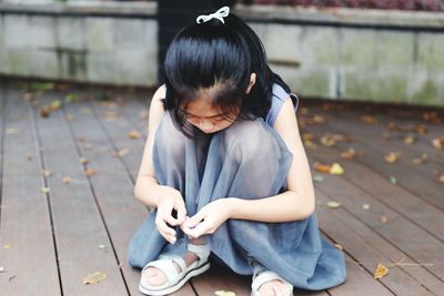 Full length of girl crouching on floorboard