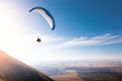 Low angle view of person paragliding against sky