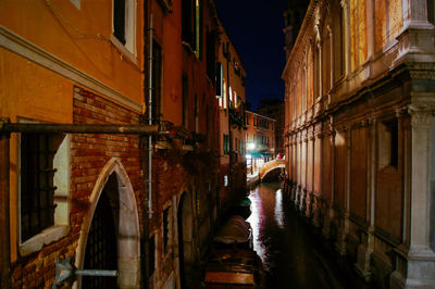 Bridge over canal amidst buildings in city at night