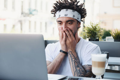 Smiling young man using laptop while sitting at table