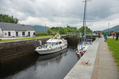 Boats moored on river in city against sky