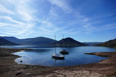 Sailboats moored in lake against sky