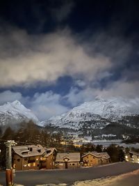 Houses on snowcapped mountain against sky