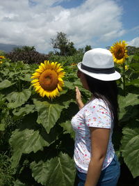 Side view of woman looking at sunflower at farm