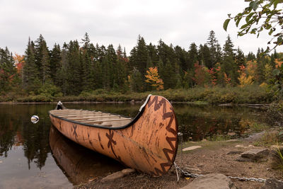 Boat on land by lake against sky