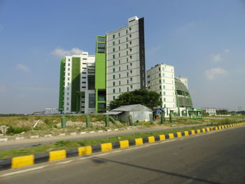 Road by buildings against sky in city