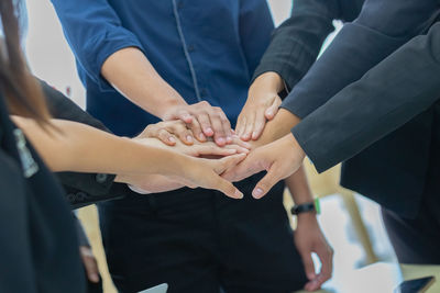 Midsection of business people stacking hands