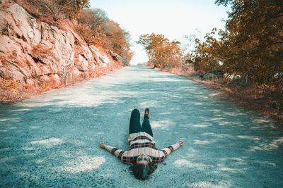 Woman lying on road against sky