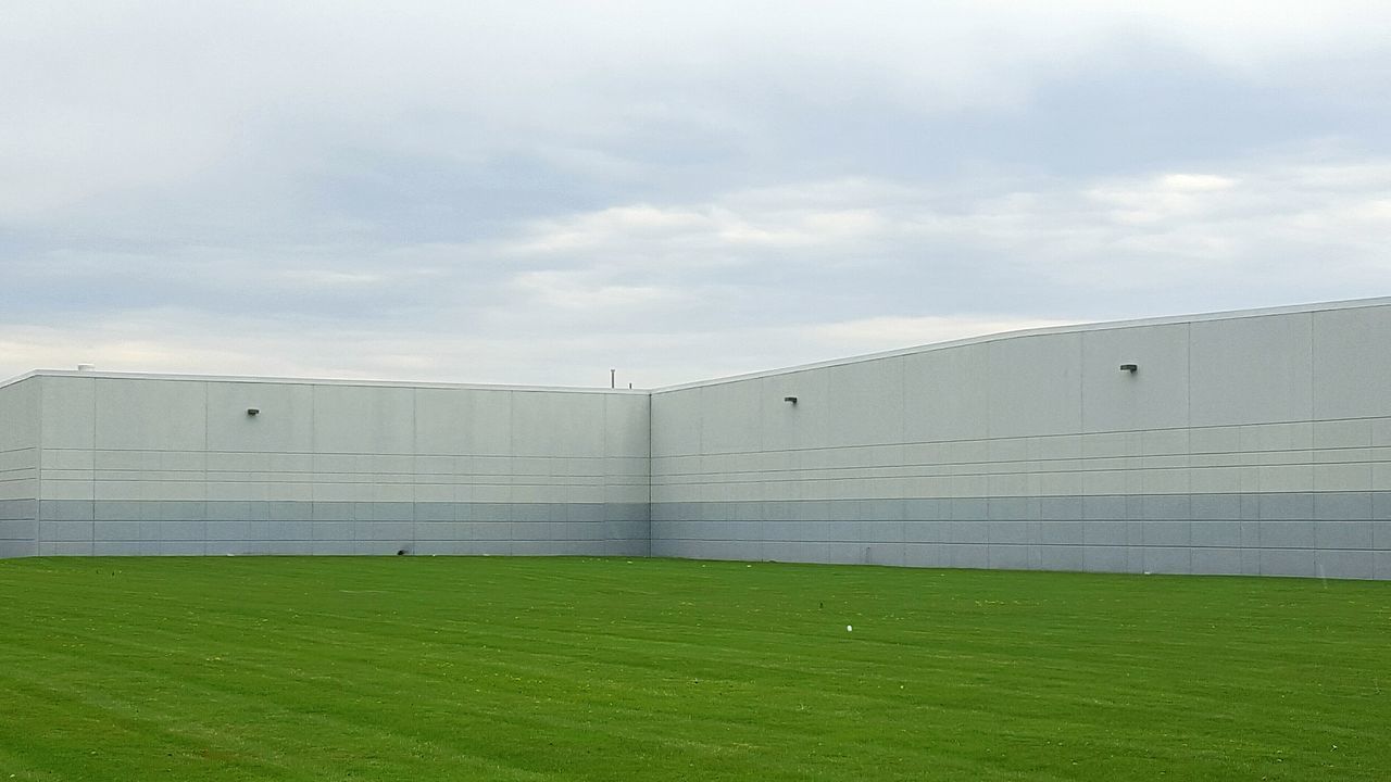 architecture, grass, built structure, building exterior, sky, green color, grassy, cloud - sky, field, day, outdoors, cloudy, no people, building, cloud, nature, low angle view, lawn, overcast, history