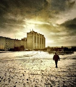 Woman standing on city street against cloudy sky