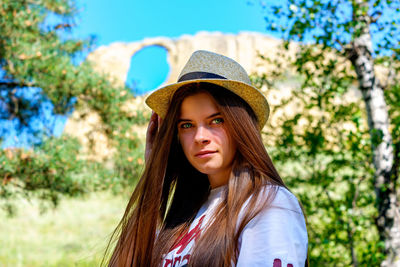 Portrait of beautiful woman wearing hat against trees