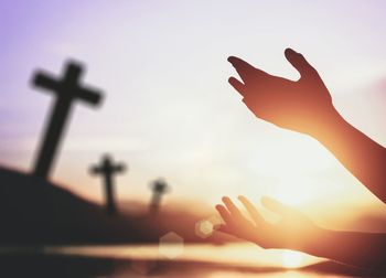 Close-up of silhouette hand against sky during sunset