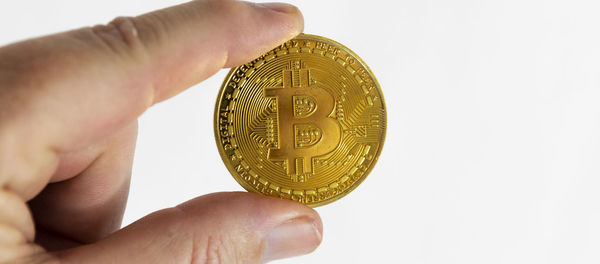 Close-up of hand holding crystal ball against white background