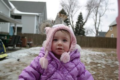 Portrait of cute girl with squirrel on head