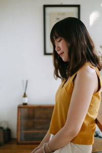 Woman looking away while standing at home