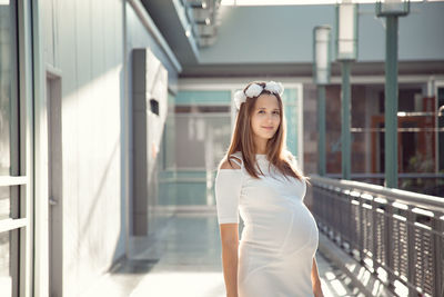 Portrait of smiling young woman standing against white wall