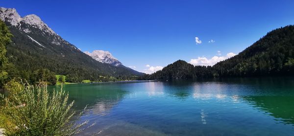 Scenic view of lake and mountains against blue sky