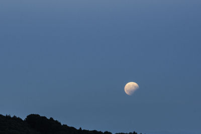 Low angle view of moon against clear blue sky