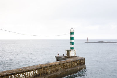 Lighthouse by sea against sky