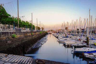 Boats moored at harbor against sky during sunset