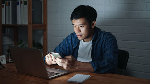 Mid adult man using mobile phone while sitting on table