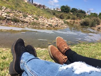 Low section of men sitting on rock by water